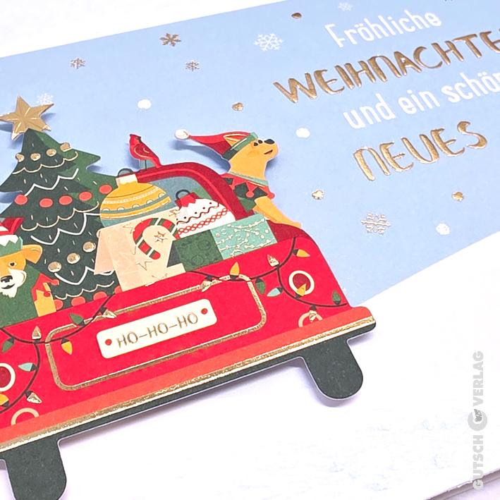 Eine festliche Weihnachtskarte mit einem roten Auto, das einen Baum und Geschenke trägt, mit einem Hund und deutschem Feiertagstext auf Hellblau.