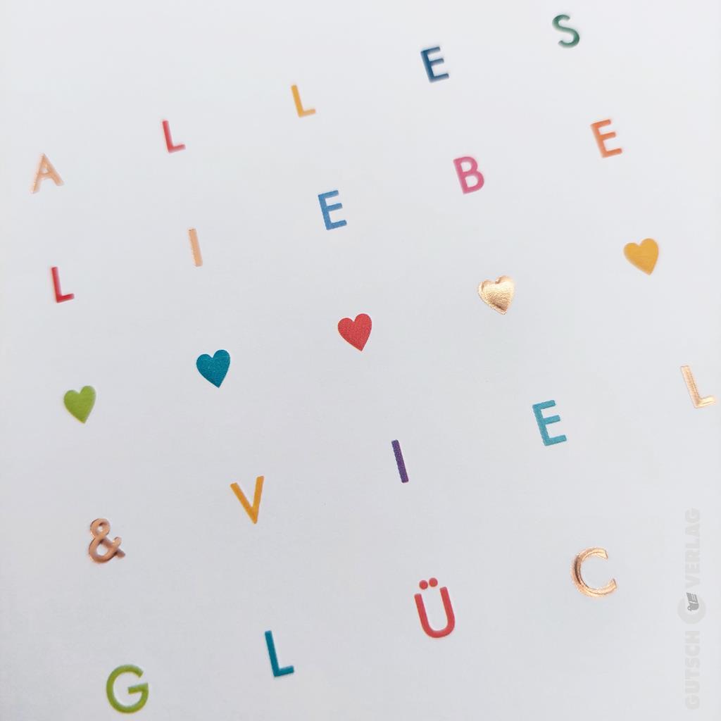 Auf einer weißen Karte sind bunte verstreute Buchstaben mit den Buchstaben „Alles Liebe“ und „Viel Glück“ zu sehen, dazwischen kleine Herzsymbole.