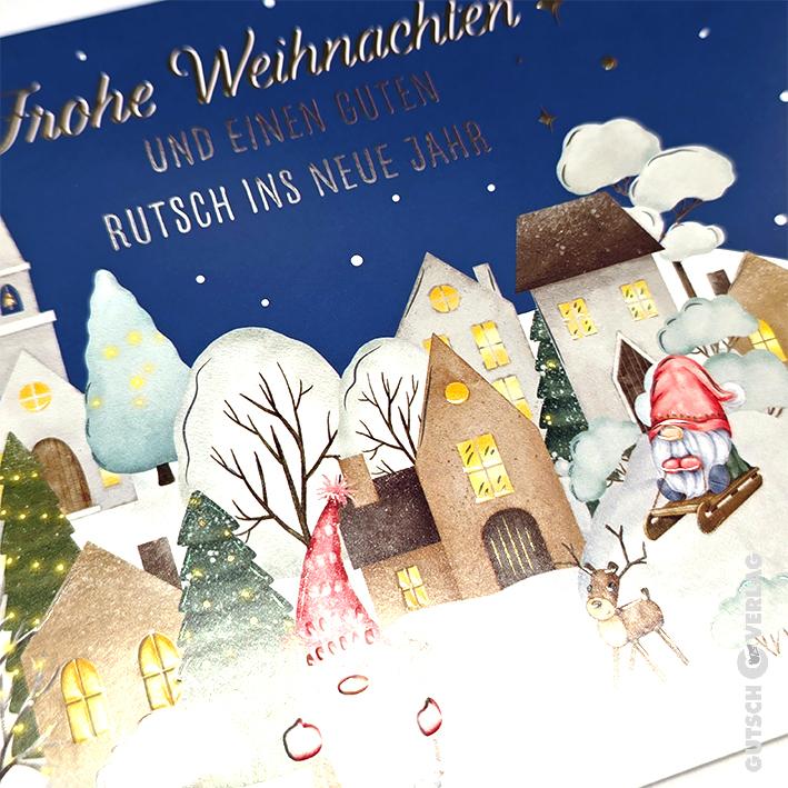 Eine festliche Weihnachtskarte mit einem verschneiten Dorf mit Zwergen, einem Rentier und leuchtenden Häusern unter einem Sternenhimmel.