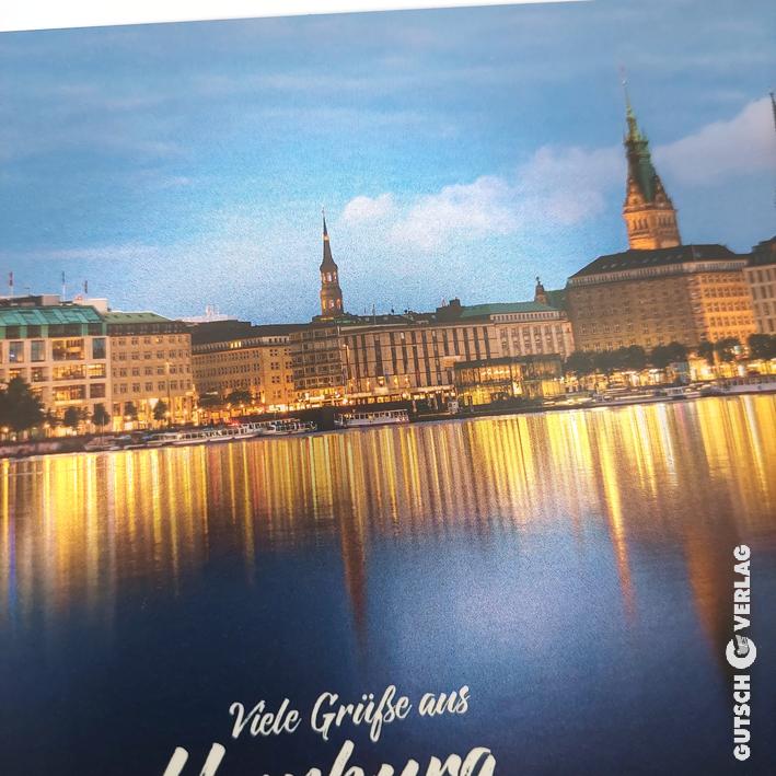 Malerische Aussicht auf die Hamburger Skyline in der Abenddämmerung, die sich im Wasser mit historischen Gebäuden und Türmen spiegelt.