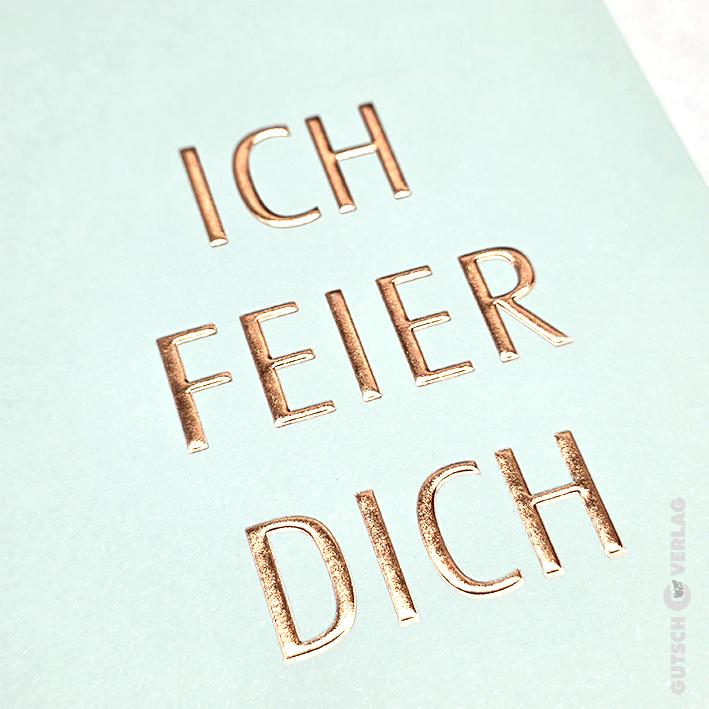 Auf einer hellmintgrünen Karte ist der deutsche Text ICH FEIER DICH in glänzenden, metallisch-kupferfarbenen Buchstaben eingeprägt.