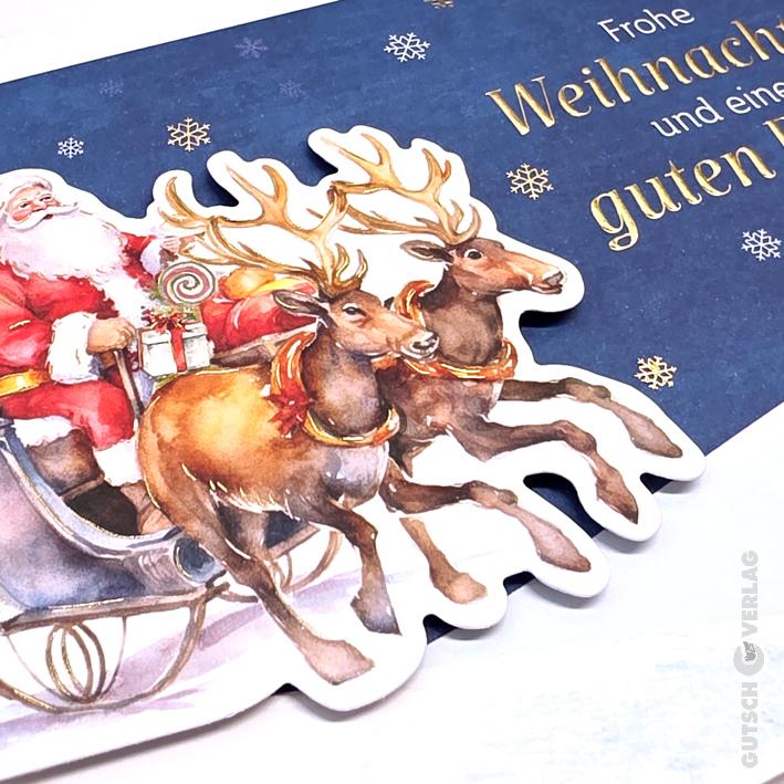 Eine Weihnachtskarte zeigt eine gestanzte Illustration des Weihnachtsmanns in einem Schlitten, der von zwei Rentieren gezogen wird, auf blauem Hintergrund.