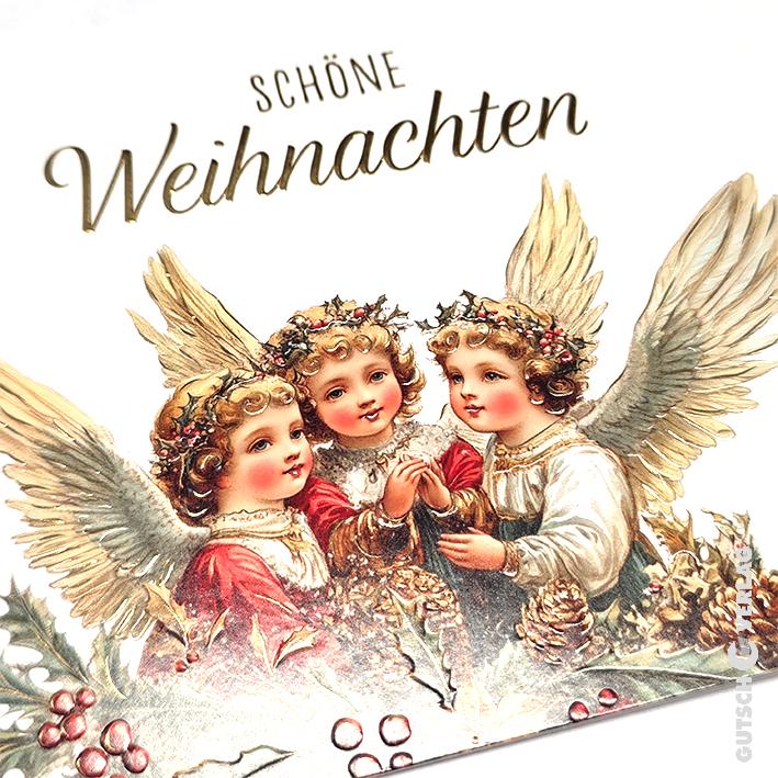 Eine Weihnachtskarte im Vintage-Stil zeigt drei geflügelte Engel mit Stechpalmenkränzen, umgeben von Tannenzapfen und roten Beeren.
