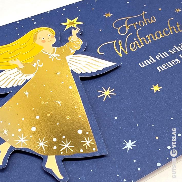 Eine blaue Weihnachtsgrußkarte mit einem goldenen Engel, der vor einem Hintergrund aus verstreuten Sternen nach einem Stern greift.
